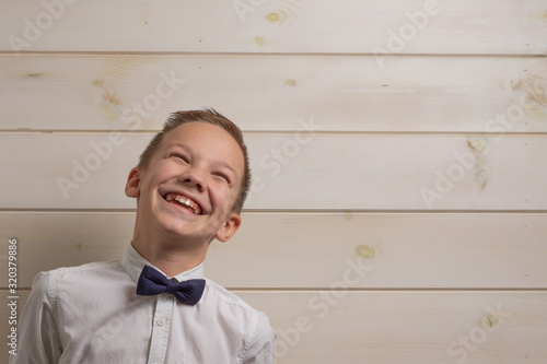 A boy of 10 years old is smiling on the background of a wooden wall.