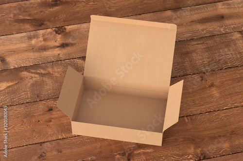 Blank cardboard wide flat box with opened hinged flap lid on dark wooden background. Clipping path around box mock up. 3d illustration