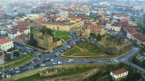 Drone footage of Paco dos Condes de Barcelos in the European city of Barcelos, Portugal on a cloudy day with a white sky above and usual traffic driving through the street
