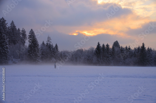Person in Schneegestöber bei Sonnenuntergang