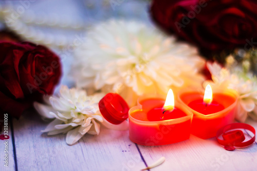 two red burning burning candles hearts flowers bow close up