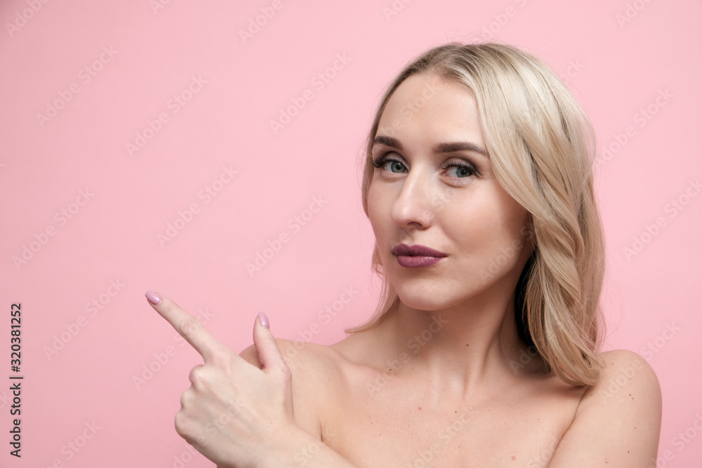 Beautiful blond woman with naked shoulders on pastel pink background. Beauty, cosmetics and skin care concept Beautiful blond woman with naked shoulders on pastel pink background. Beauty, cosmetics and skin care concept