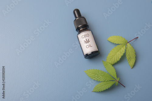 CBD oil with leaves on a blue background with copy space 