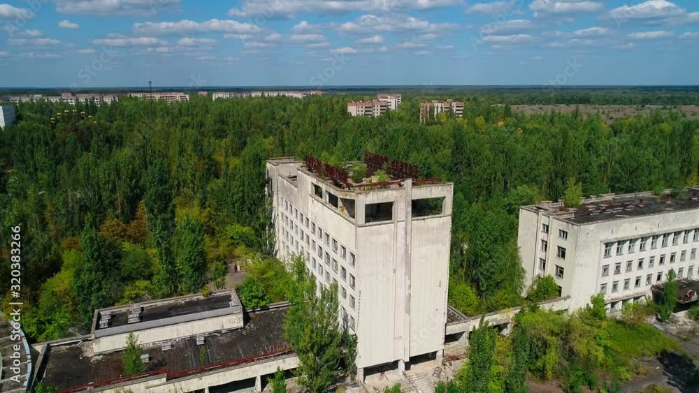 Aerial view of abandoned hotel and streets overgrown with trees in city Pripyat near Chernobyl nuclear power plant. Cyrillic inscription Aerial view of abandoned hotel and streets overgrown with trees in city Pripyat near Chernobyl nuclear power plant. Cyrillic inscription
