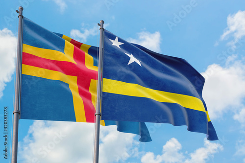 Curacao and Aland Islands flags waving in the wind against white cloudy blue sky together. Diplomacy concept, international relations.