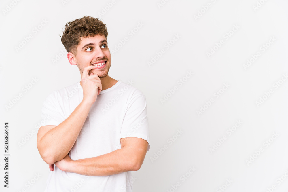 Young blond curly hair caucasian man isolated relaxed thinking about something looking at a copy space. Young blond curly hair caucasian man isolated relaxed thinking about something looking at a copy space.