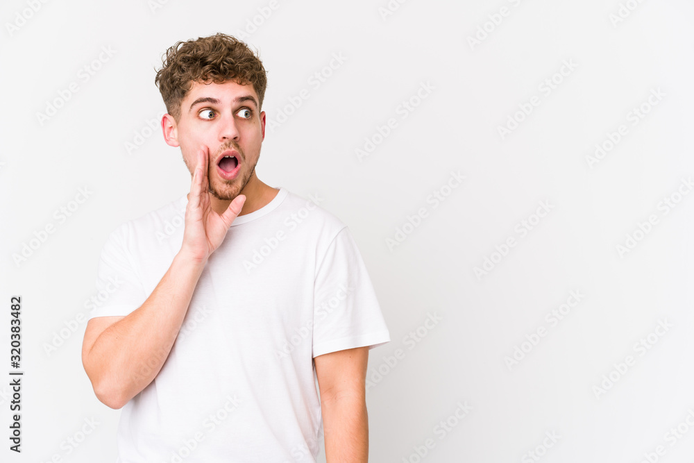 Young blond curly hair caucasian man isolated is saying a secret hot braking news and looking aside Young blond curly hair caucasian man isolated is saying a secret hot braking news and looking aside