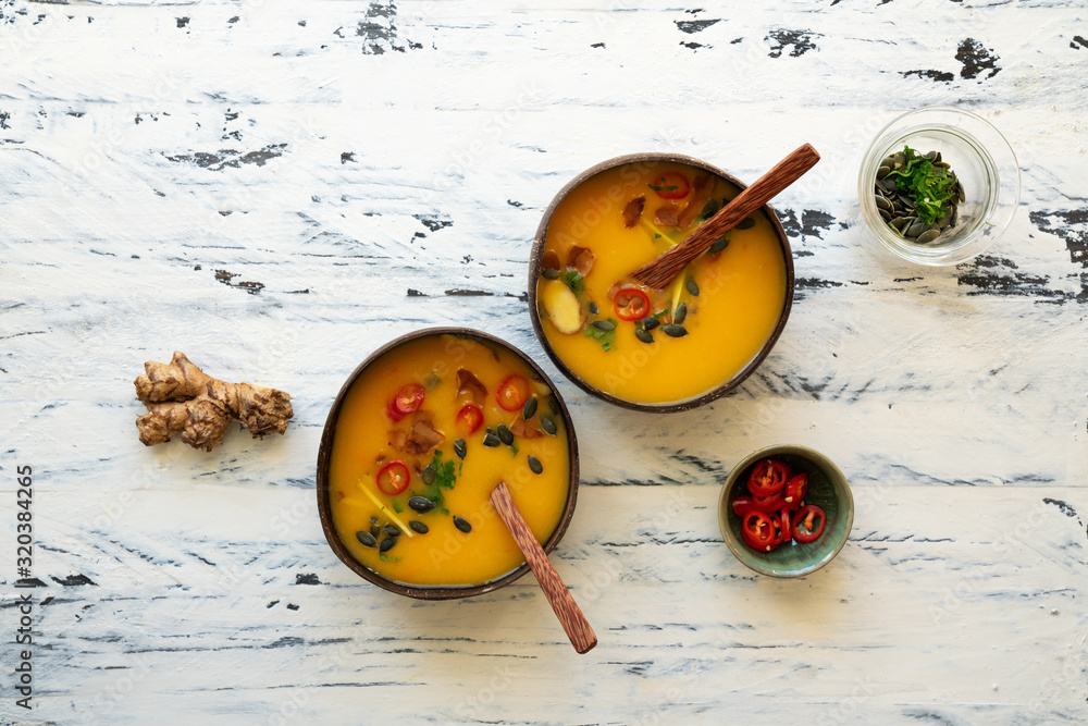 Freshly made creamy pumpkin soup served in coconut bowls with asian seasonings and pumpkin seeds Freshly made creamy pumpkin soup served in coconut bowls with asian seasonings and pumpkin seeds