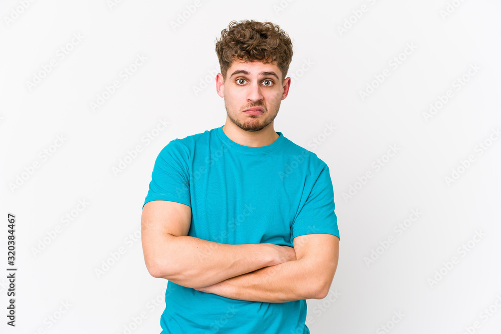 Fototapeta premium Young blond curly hair caucasian man isolated unhappy looking in camera with sarcastic expression.
