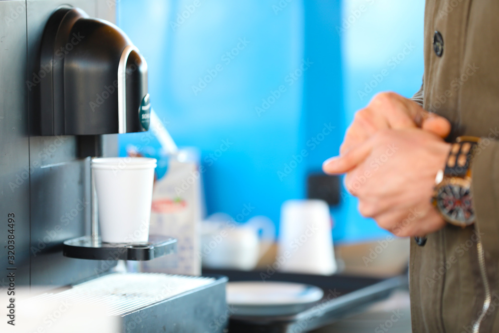 Man is getting coffee from coffee machine Man is getting coffee from coffee machine