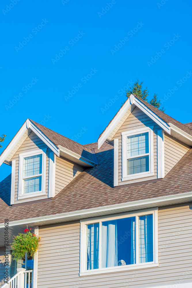 A perfect neighborhood. Houses in suburb at Summer in the north America. Top of a luxury house with nice window over blue and white sky.