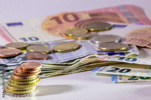 Stapel Euro-Münzen aus 2 Euro, 1 Euro und Cent-Münzen mit einem Haufen Bargeld aus Geldscheinen und EURO-Münzen zeugt von Reichtum in der Finanzwelt und schnelles Geld