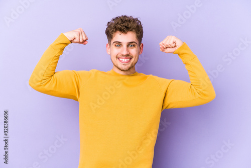 Young blond curly hair caucasian man isolated showing strength gesture with arms, symbol of feminine power