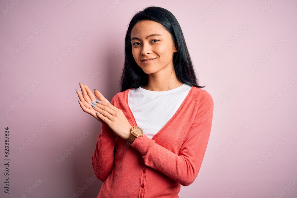 Obraz premium Young beautiful chinese woman wearing casual sweater over isolated pink background clapping and applauding happy and joyful, smiling proud hands together