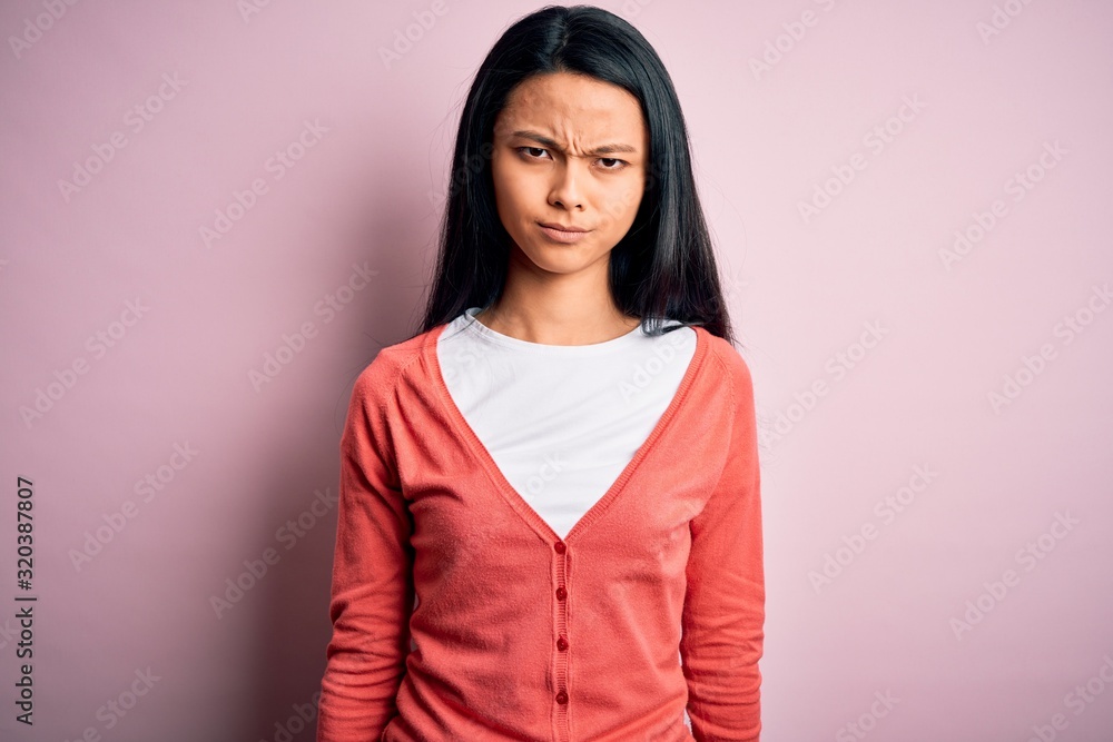 Young beautiful chinese woman wearing casual sweater over isolated pink background skeptic and nervous, frowning upset because of problem. Negative person. Young beautiful chinese woman wearing casual sweater over isolated pink background skeptic and nervous, frowning upset because of problem. Negative person.