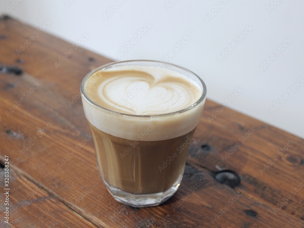 A cup of coffee with latte art, a cappuccino or a moka rich in caffeine with some milk, on the table in a trendy hipster cafe. A cup of coffee with latte art, a cappuccino or a moka rich in caffeine with some milk, on the table in a trendy hipster cafe.