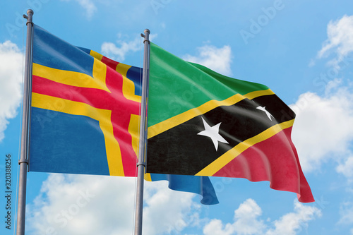 Saint Kitts And Nevis and Aland Islands flags waving in the wind against white cloudy blue sky together. Diplomacy concept, international relations. photo