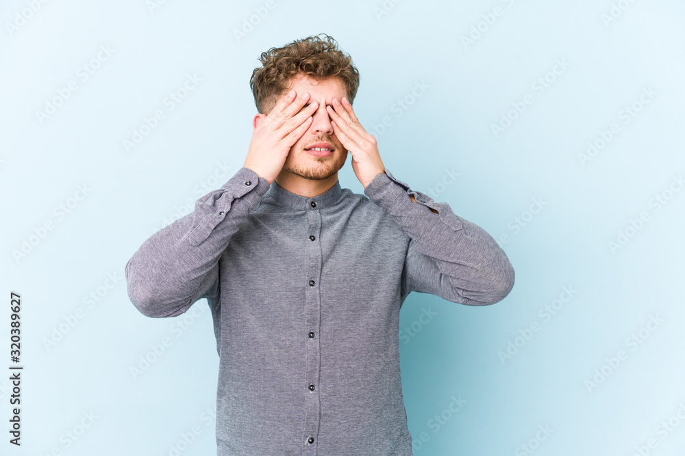 Young blond curly hair caucasian man isolated afraid covering eyes with hands. Young blond curly hair caucasian man isolated afraid covering eyes with hands.