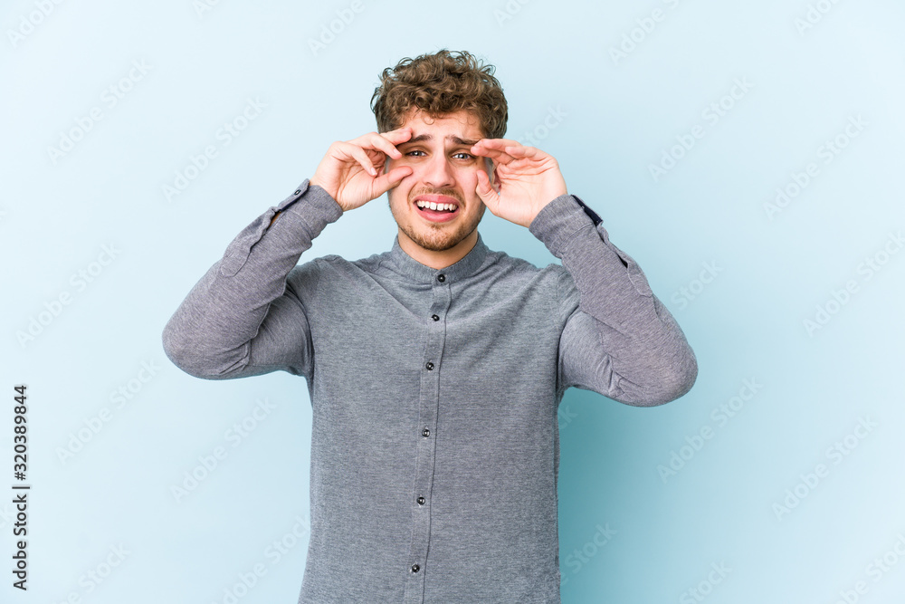 Young blond curly hair caucasian man isolated crying, unhappy with something, agony and confusion concept. Young blond curly hair caucasian man isolated crying, unhappy with something, agony and confusion concept.