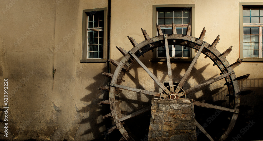 water wheel before a wall with sunlight