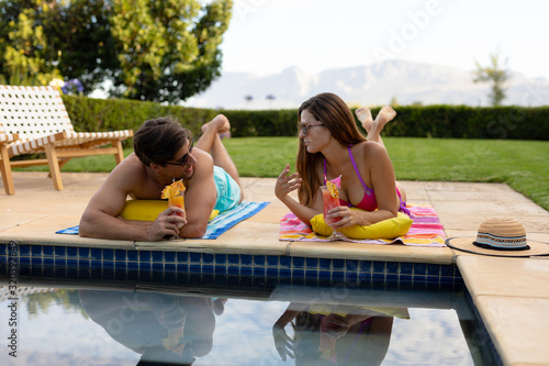 Happy young couple relaxing near the swimming pool