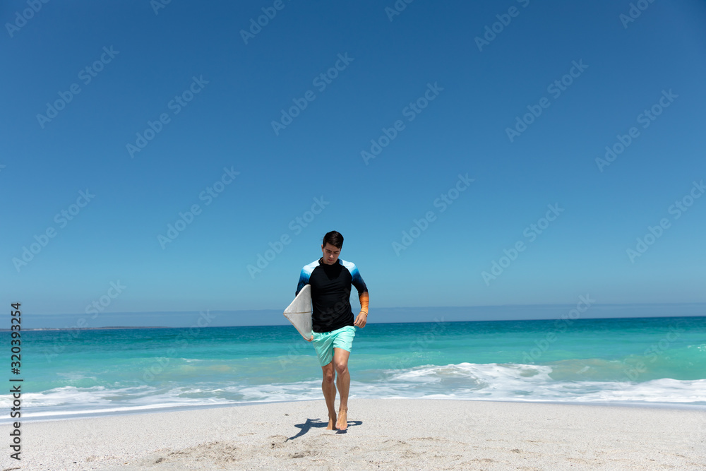 Young man walking with surfboard at the beach Young man walking with surfboard at the beach
