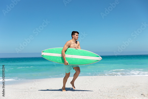 Young man with surfboard at the beach © wavebreak3