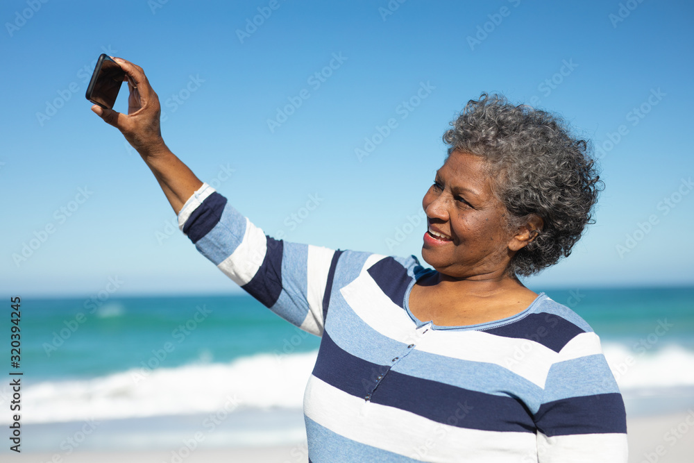 Old woman taking selfies at the beach