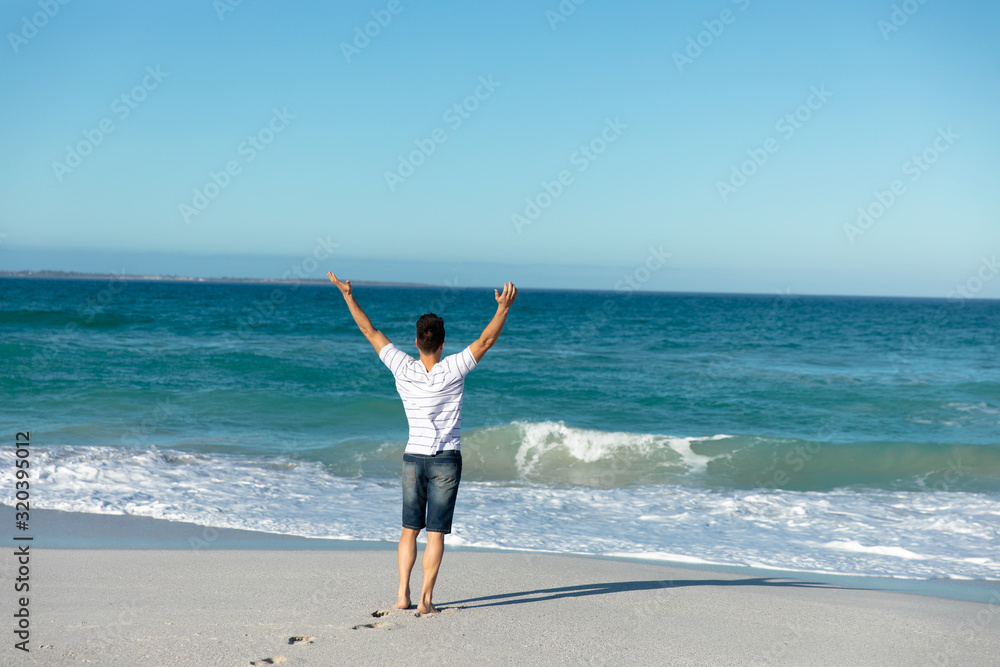 Young man relaxing at the beach arms up