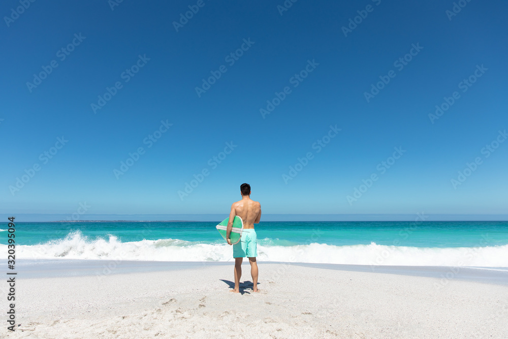 Young man with surfboard at the beach