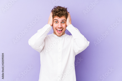 Young blond curly hair caucasian man isolated screaming, very excited, passionate, satisfied with something. © Asier