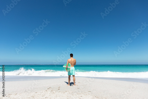 Young man with surfboard at the beach © wavebreak3