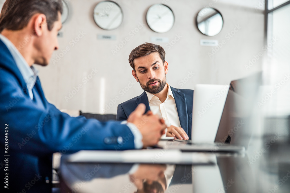 Manager sitting at the desk with his colleague Manager sitting at the desk with his colleague
