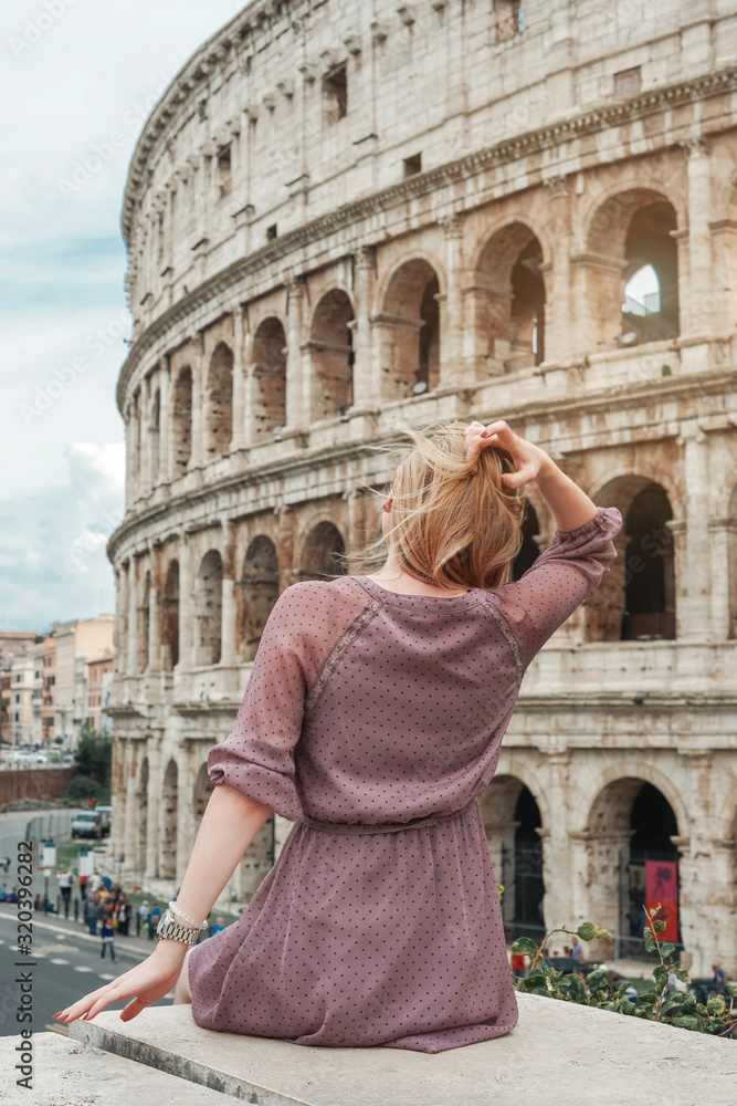 Travel in Rome. Back view of beautiful girl visiting Colosseum landmark. Summer holidays in Italy.