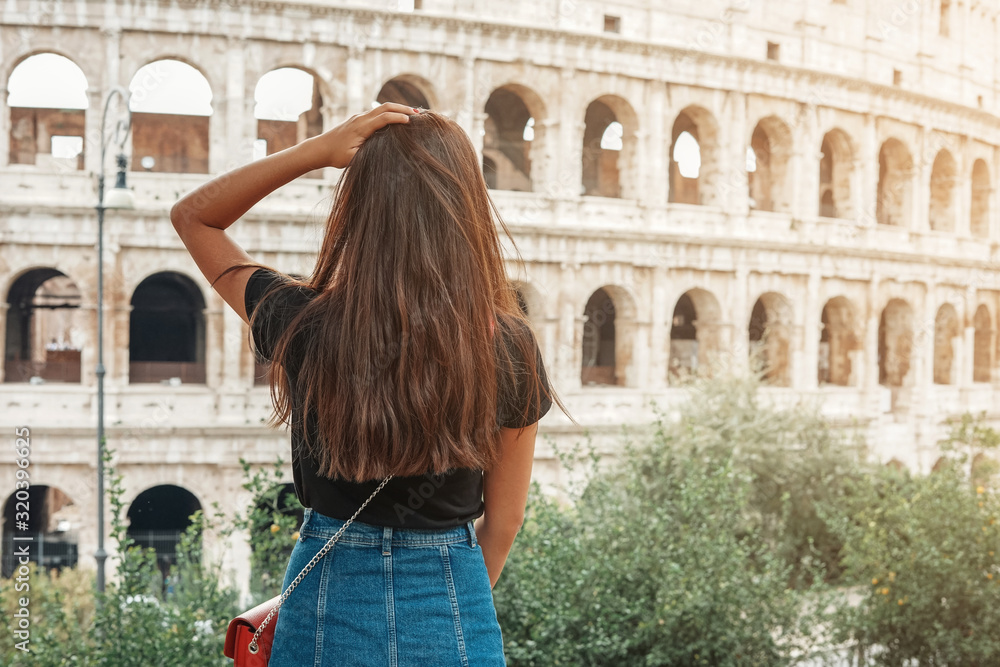 Travel in Rome. Back view of beautiful girl visiting Colosseum landmark. Summer holidays in Italy.