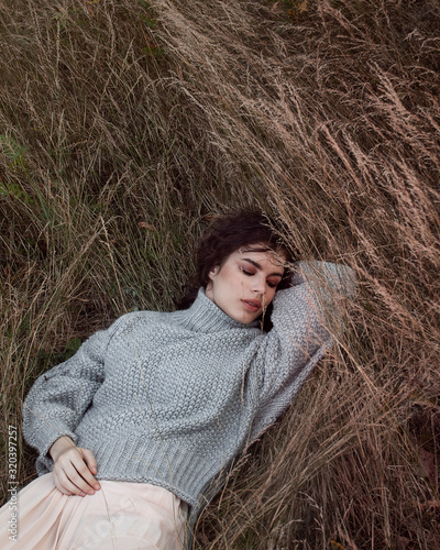  Curly girl in a sweater walks through the apple orchard