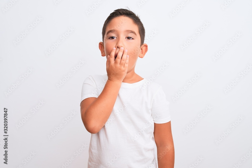 Beautiful kid boy wearing casual t-shirt standing over isolated white background bored yawning tired covering mouth with hand. Restless and sleepiness. Beautiful kid boy wearing casual t-shirt standing over isolated white background bored yawning tired covering mouth with hand. Restless and sleepiness.
