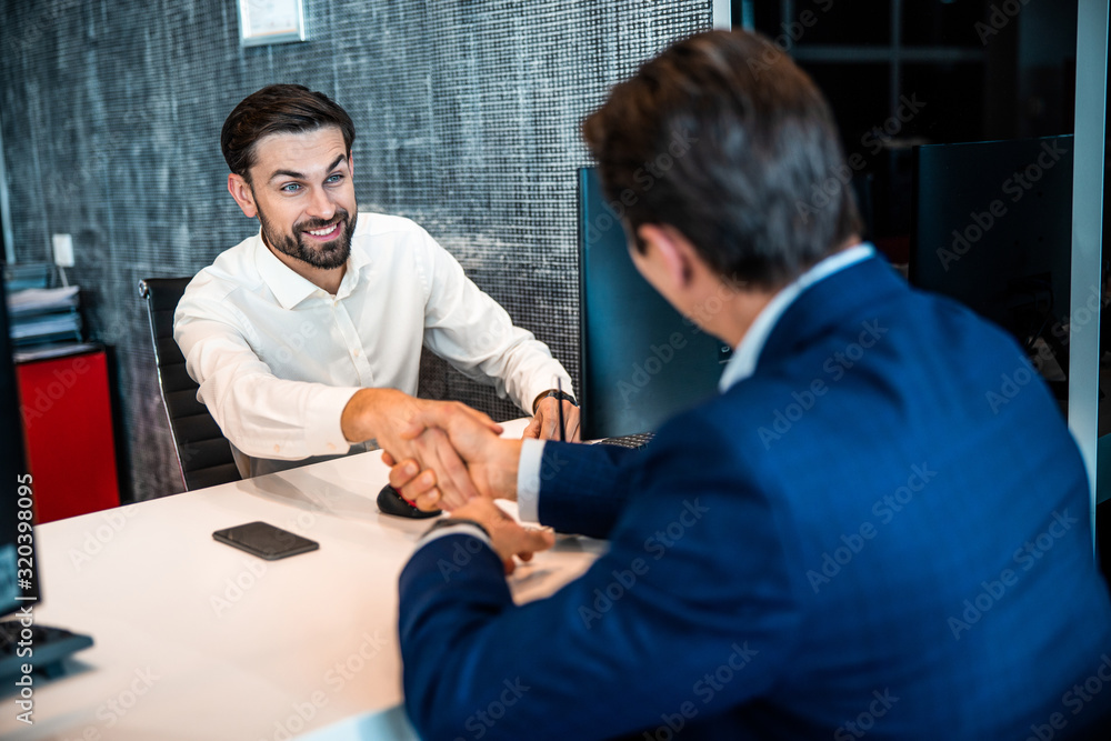 Smiling office worker shaking his customers hand Smiling office worker shaking his customers hand