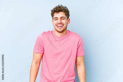 Young blond curly hair caucasian man isolated laughs and closes eyes, feels relaxed and happy.