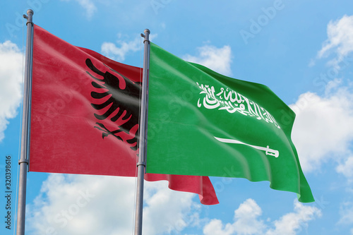 Saudi Arabia and Albania flags waving in the wind against white cloudy blue sky together. Diplomacy concept, international relations.