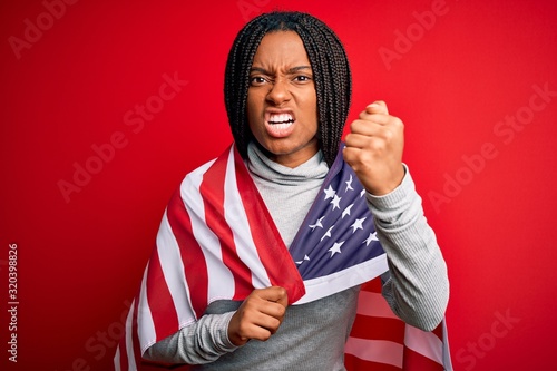 Young african american patriotic woman wearing united states of america flag on independence day annoyed and frustrated shouting with anger, crazy and yelling with raised hand, anger concept