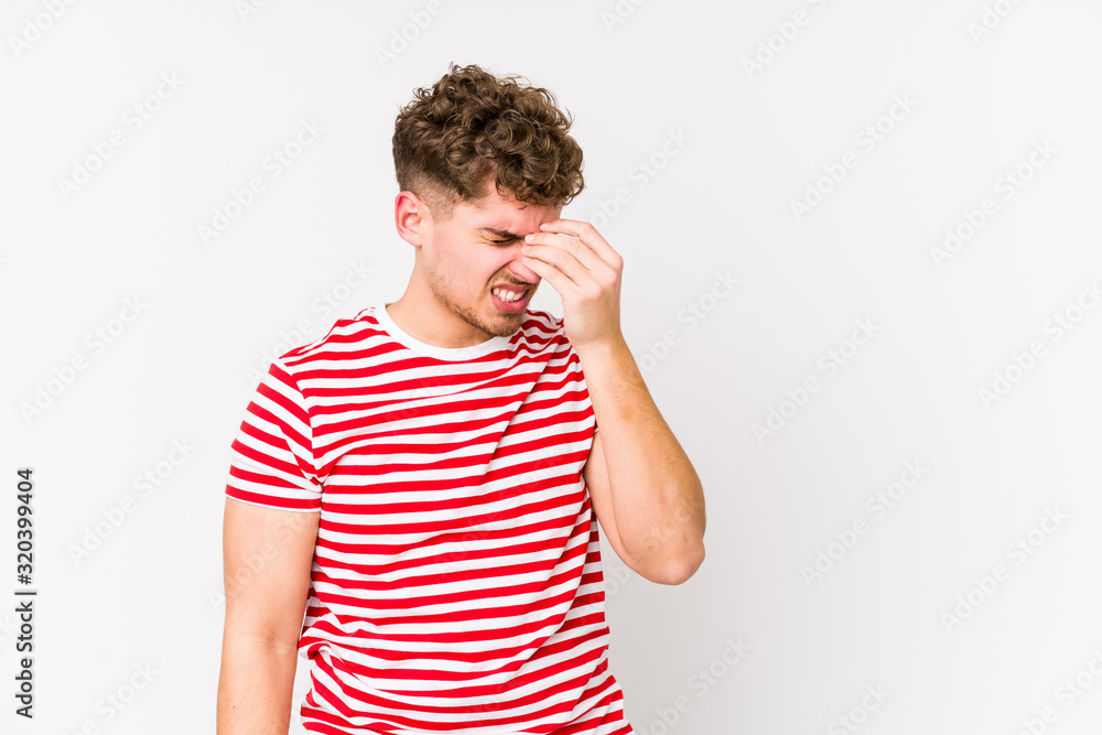 Young blond curly hair caucasian man isolated having a head ache, touching front of the face. Young blond curly hair caucasian man isolated having a head ache, touching front of the face.