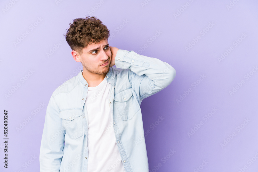 Fototapeta premium Young blond curly hair caucasian man isolated touching back of head, thinking and making a choice.