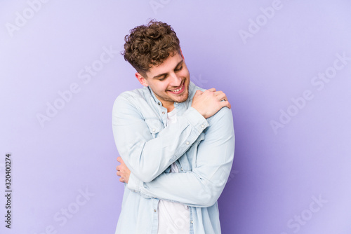 Young blond curly hair caucasian man isolated hugs, smiling carefree and happy.