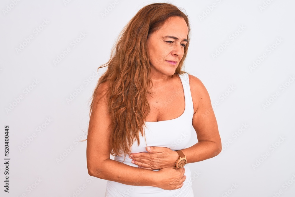 Middle age mature woman standing over white isolated background with hand on stomach because indigestion, painful illness feeling unwell. Ache concept. Middle age mature woman standing over white isolated background with hand on stomach because indigestion, painful illness feeling unwell. Ache concept.
