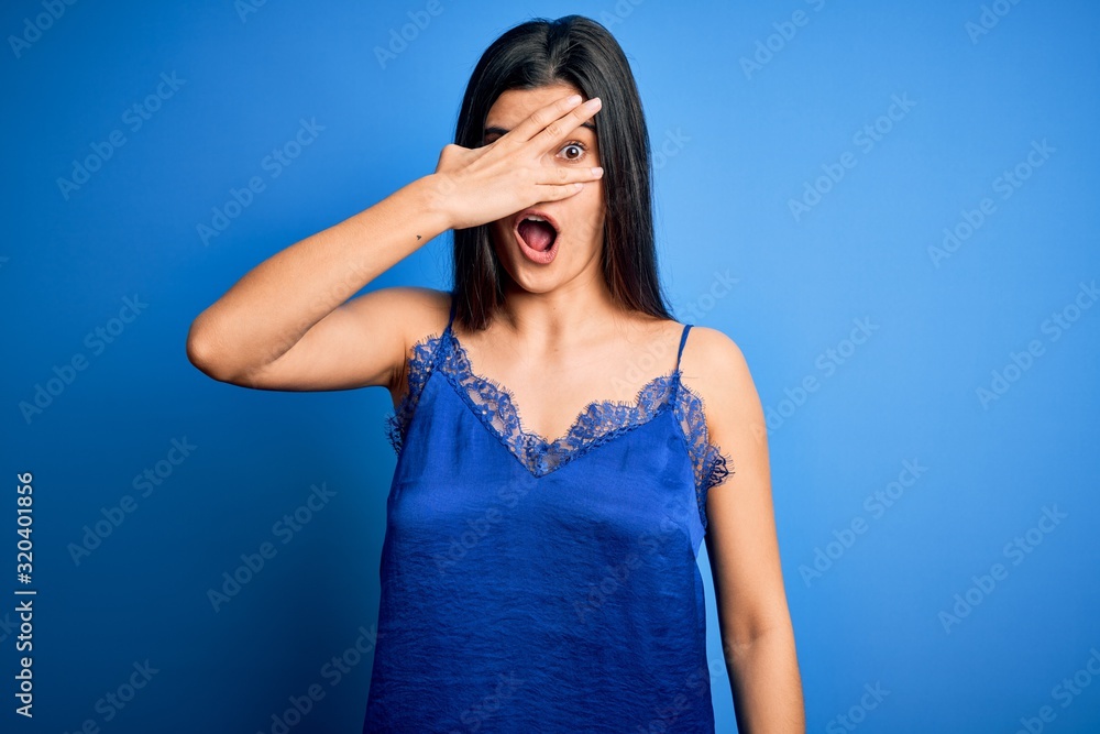 Young beautiful brunette woman wearing elegant and comfortable blue lingerie underwear peeking in shock covering face and eyes with hand, looking through fingers with embarrassed expression. Young beautiful brunette woman wearing elegant and comfortable blue lingerie underwear peeking in shock covering face and eyes with hand, looking through fingers with embarrassed expression.