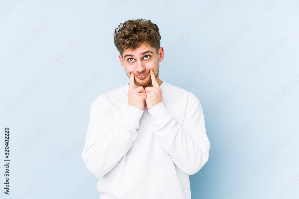 Young blond curly hair caucasian man isolated doubting between two options. Young blond curly hair caucasian man isolated doubting between two options.