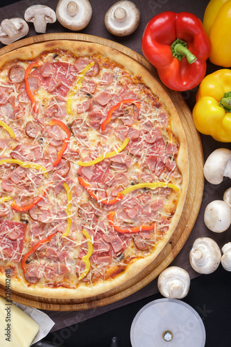 Delicious pizza. Large meat pizza with bacon, sausage, salami, pepperoni and olives. Homemade delicious italian pizza on wooden table for dinner. Italian cuisine.