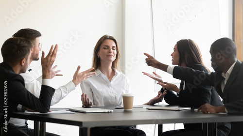 While stressed colleagues screaming to young businesswoman she meditating photo