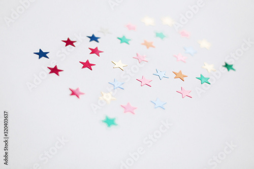 Colorful stars confetti or glitter on white background. Party backdrop. Stylish atmospheric image. Happy birthday concept. Holiday decorations. Magic and Christmas.